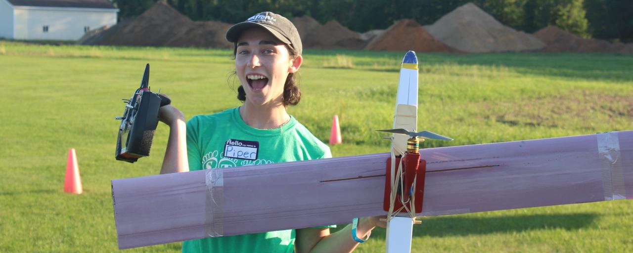 Summer staff member poses with her plane after STEPS Flight Night